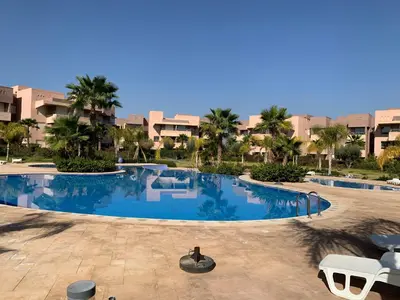 a large swimming pool in a resort with palm trees at Marrakech Prestigia Jade Golf Piscine in Marrakech