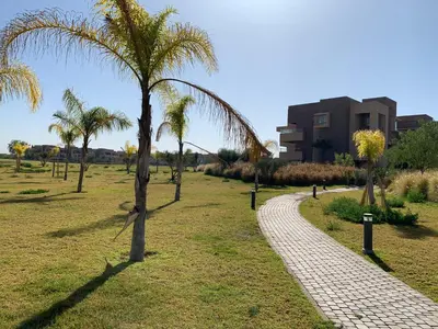 a cobblestone path in a park with palm trees at Marrakech Prestigia Jade Golf Piscine in Marrakech