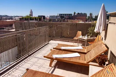a balcony with chairs and a table and an umbrella at Riad Dar Jabel in Marrakech