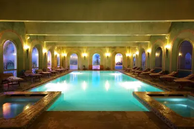 a large swimming pool in a building with chairs at Palmeraie Golf Suites By Pickalbatros in Marrakech