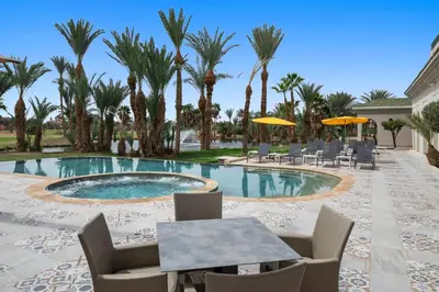 a pool with chairs and tables and palm trees at Palmeraie Golf Suites By Pickalbatros in Marrakech