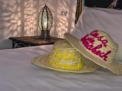 two straw hats sitting on a bed with a lamp at Casa De Marrakech Riad Guest House in Marrakech