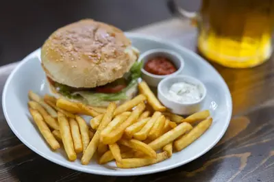 a plate with a hamburger and french fries and dips at Casa De Marrakech Riad Guest House in Marrakech