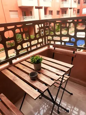 a wooden bench with a potted plant on a table at La saphir marrakech in Marrakech