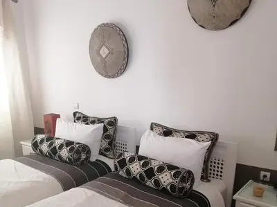 a bedroom with two beds with pillows and a clock on the wall at Dar 14 Marrakech in Marrakech