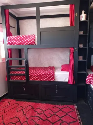 a bedroom with two bunk beds with a red rug at Stork Marrakech Luxury Hostel in Marrakech