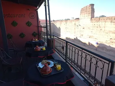a table with food on a balcony with a view of the wall at Stork Marrakech Luxury Hostel in Marrakech