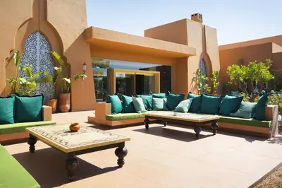 a patio with blue couches and a table at Hotel Riu Tikida Palmeraie - All Inclusive in Marrakech