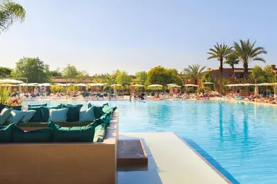 a large swimming pool with chairs and umbrellas at Hotel Riu Tikida Palmeraie - All Inclusive in Marrakech