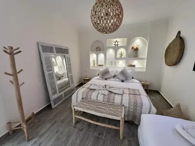 a white bedroom with a bed and a mirror at RIAD RIME QOUSSAI in Marrakech