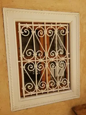 a window with a white iron grate on a wall at Hostel Laksour in Marrakech