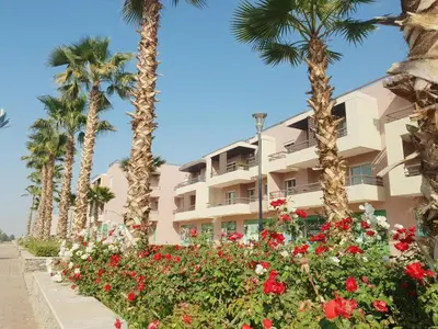 a building with palm trees and flowers in front of it at RIAD GARDEN LUXURY AGDAL in Marrakech