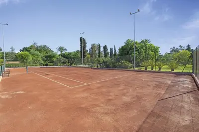 a tennis court with a net in a park at Hotel Riu Tikida Garden - Adults Only - All Inclusive in Marrakech