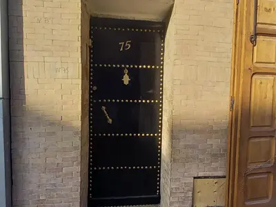 a black door with the number in a brick wall at studio Dar Rmila in Marrakech