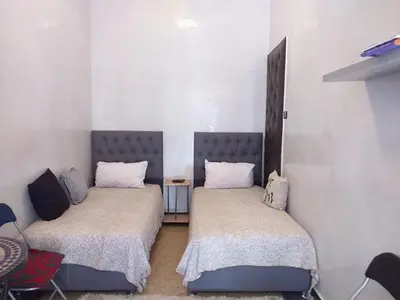 two beds in a room with white walls at studio Dar Rmila in Marrakech