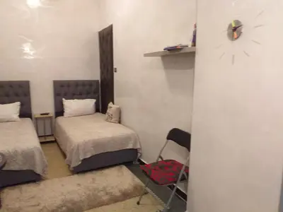 a room with two beds and a clock on the wall at studio Dar Rmila in Marrakech