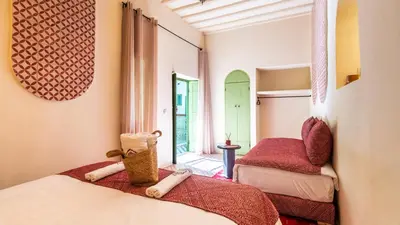 a bedroom with two beds and a mirror at Riad Dar Tiflet in Marrakech