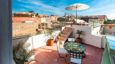 a balcony with a table and chairs and an umbrella at Riad Dar Tiflet in Marrakech