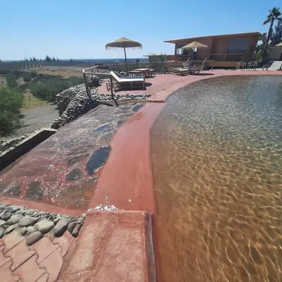 a pool of water with a bench and an umbrella at Le Parc des Oliviers Ecolodge in Marrakech