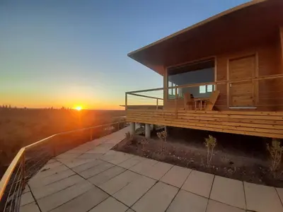 a house with a balcony with the sunset in the background at Le Parc des Oliviers Ecolodge in Marrakech