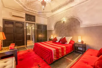 a bedroom with a red bed and a couch at Riad Espoir, Riad de charme en exclusivité dans la médina de Marrakech in Marrakech
