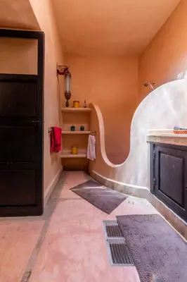 a bathroom with orange walls and a sink and shelves at Riad Espoir, Riad de charme en exclusivité dans la médina de Marrakech in Marrakech