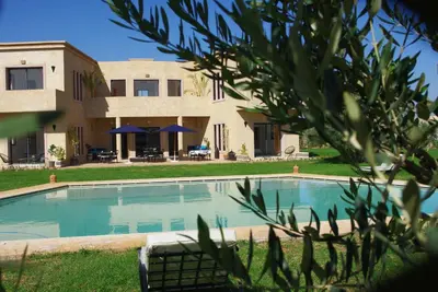 a swimming pool in front of a house at LE JASMIN DE MARRAKECH in Marrakech