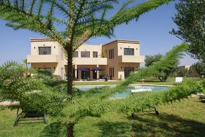 a building with a pool in front of a house at LE JASMIN DE MARRAKECH in Marrakech