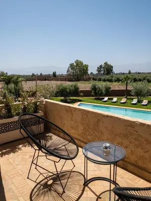 a patio with two chairs and a table and a pool at LE JASMIN DE MARRAKECH in Marrakech
