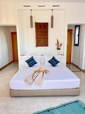 a bedroom with a white bed with blue pillows at LE JASMIN DE MARRAKECH in Marrakech