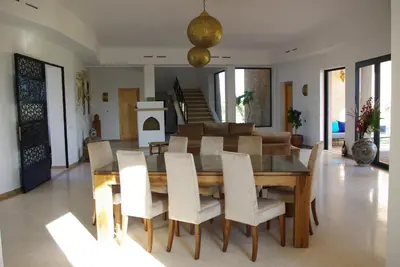 a dining room with a wooden table and white chairs at LE JASMIN DE MARRAKECH in Marrakech
