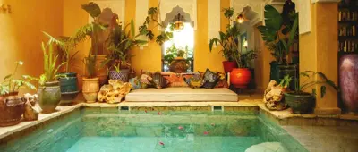 a room with a bed and a pool with plants at Riad Persephone in Marrakech
