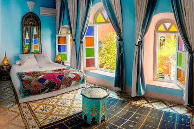 a bedroom with a bed and two windows at Riad Persephone in Marrakech
