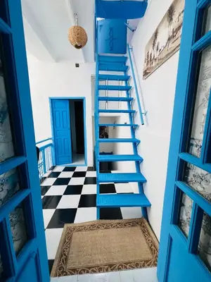 a blue staircase in a room with a checkered floor at Dar Beldi in Marrakech