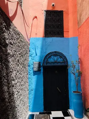 a blue and orange building with a black door at Dar Beldi in Marrakech