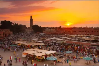 a crowd of people walking around a market at sunset at Dar Beldi in Marrakech
