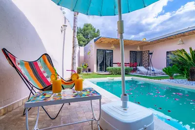 a chair and an umbrella next to a swimming pool at VILLA MARIA - Famille uniquement in Marrakech