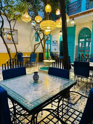a table and chairs in a courtyard with chandeliers at Riad Al Nour in Marrakech