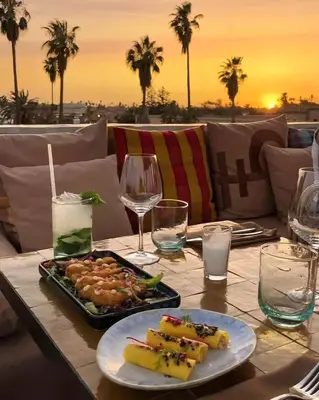 a table with a plate of food and wine glasses at La Perle de l'Atlas by Golf Resort in Marrakech