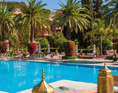 a pool at a resort with palm trees and chairs at La Perle de l'Atlas by Golf Resort in Marrakech