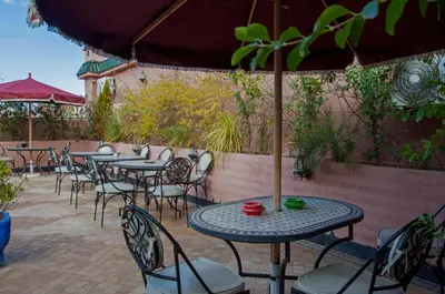 an outdoor patio with tables and chairs and an umbrella at Riad Merzouga in Marrakech