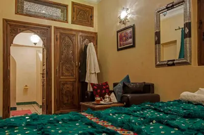 a bedroom with a bed and a chair and a mirror at Riad Merzouga in Marrakech