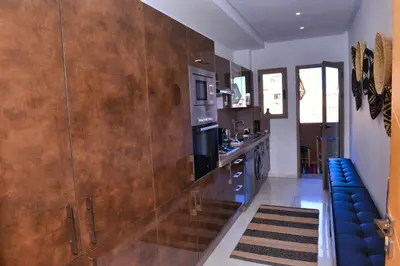a kitchen with a large wooden wall and a blue couch at Appartement de prestige climatisé à l'hivernage 400m de la Gare in Marrakech