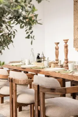 a wooden table with wooden chairs and a table with a tableclotholitics at Riad Darsahalia in Marrakech
