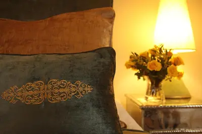 a pillow and a vase of flowers on a table with a lamp at Riad Assakina in Marrakech