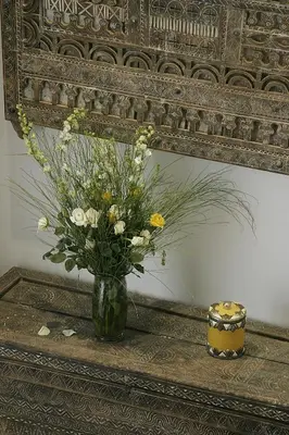 a vase of flowers on a table in front of a mirror at Riad Assakina in Marrakech