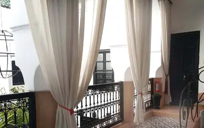 a balcony with white curtains and a railing with a staircase at Riad Gaya in Marrakech