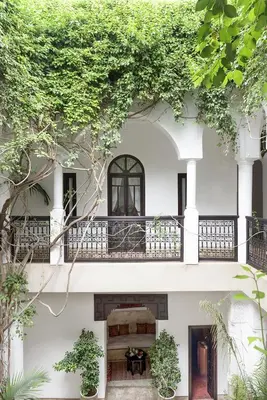 a white building with a balcony and trees at Riad Hayati in Marrakech