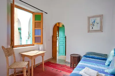 a bedroom with a bed and a table and a window at Riad Dar Aida in Marrakech