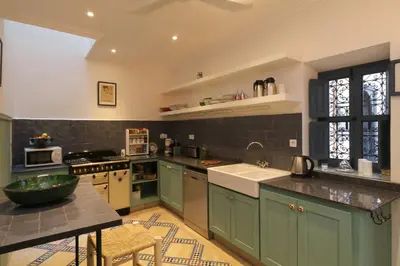 a large kitchen with green cabinets and a sink at Riad Dar Safi, privatise 6 à 8 pers, bain exterieur in Marrakech